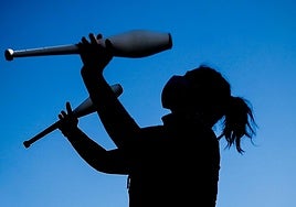 Una persona realiza malabares con unas mazas.