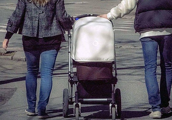 Una pareja pasea con un bebé.