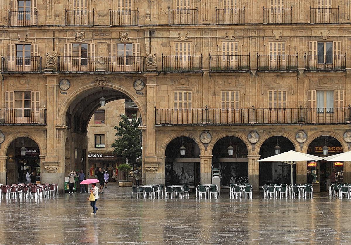 Viandantes caminan bajo la lluvia en la Plaza Mayor