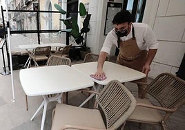 Un camarero limpia las mesas de calima.