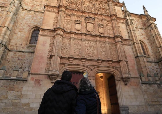 Dos personas observan la fachada de la Universidad de Salamanca.