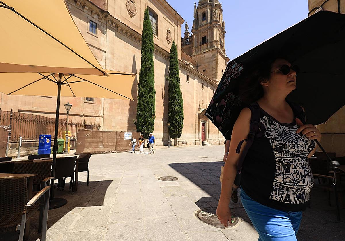 Una mujer se protege del sol con el paraguas.