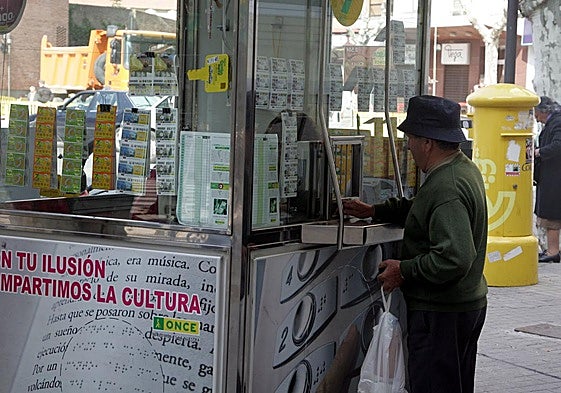 Un hombre compra un cupón en un quiosco de la ONCE.
