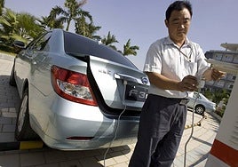 Un hombre conecta a la red eléctrica un modelo híbrido BYD (Build Your Dreams), en Shenzhen, China.