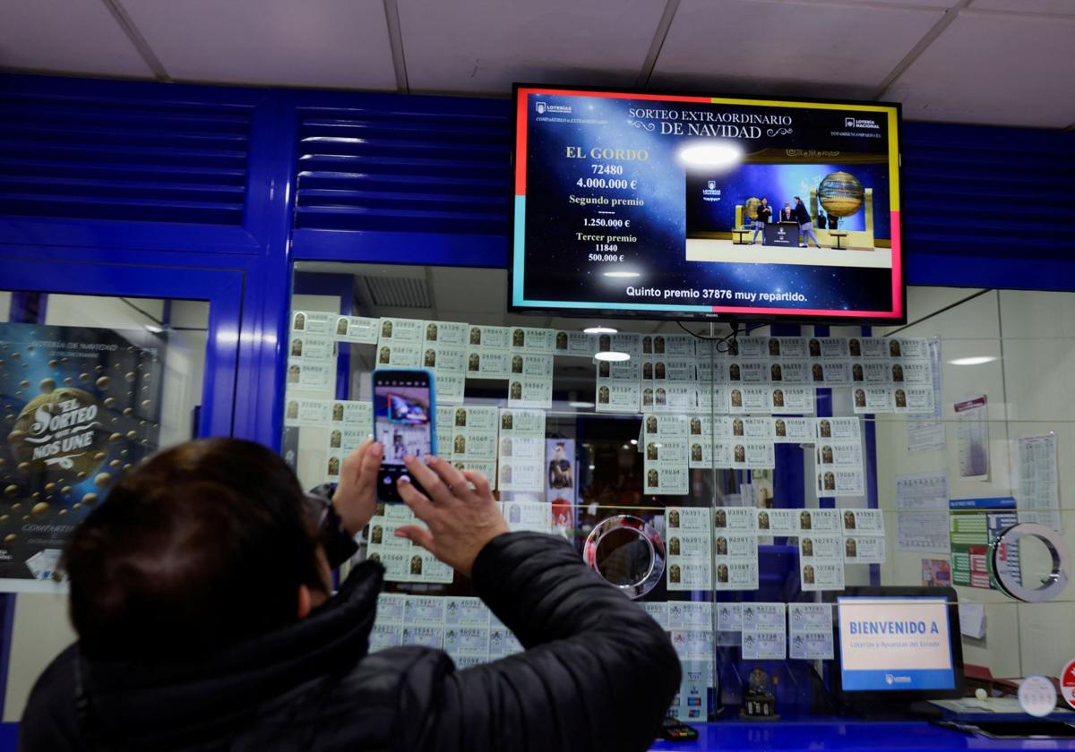 Un hombre fotografía la pantalla de una administración de lotería.