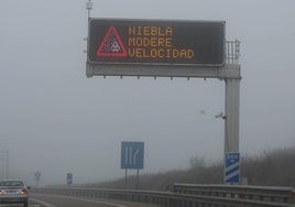 Cartel anunciador de peligro por niebla en una autovía.