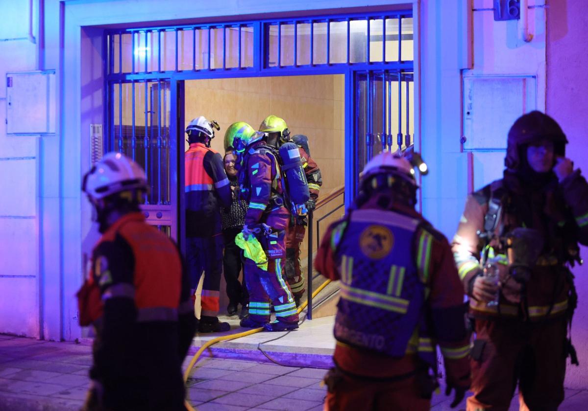 Los bomberos ayudan a salir a una mujer del edificio.
