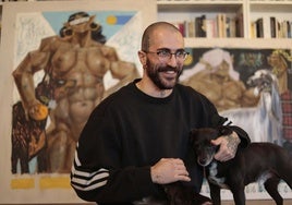 Alvar Mena en el salón de su casa junto a sus obras y a uno de sus perros.