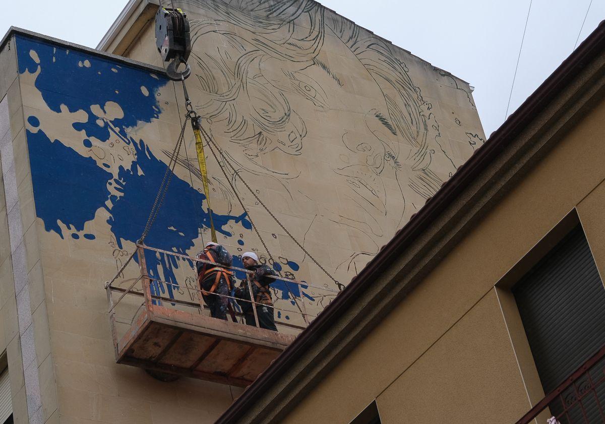 Imagen principal - Arriba, primeras líneas del nuevo mural; la grúa que sujeta la plataforma y la fachada lateral.