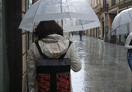 Varias personas pasean con paraguas por Salamanca un día de lluvia.