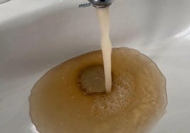 Imagen de archivo de agua turbia saliendo de un grifo.