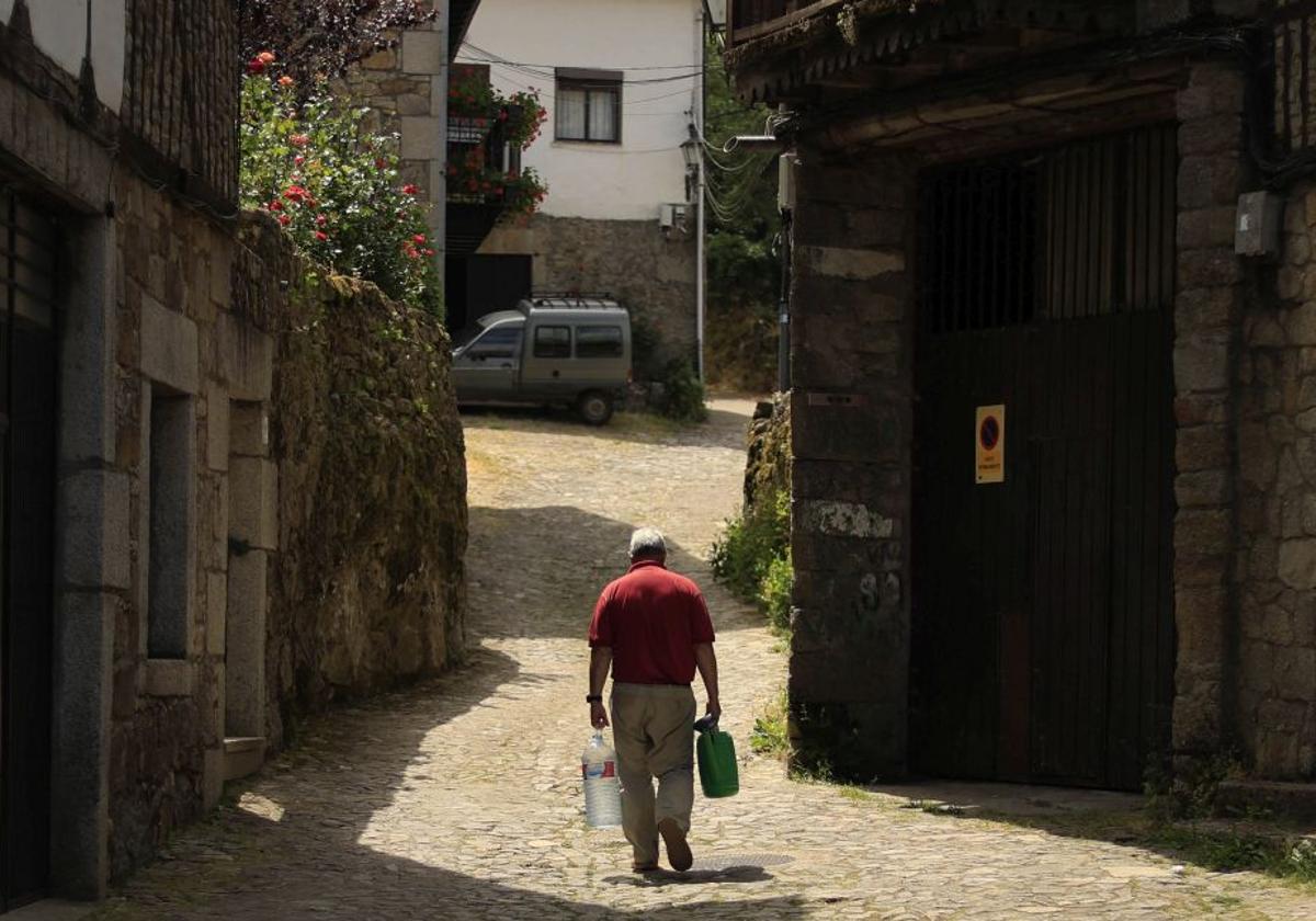 Un hombre lleva garrafas de agua en un pueblo de Salamanca.