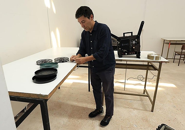 Alberto Cabrera junto a un proyector de 16 mm y varias bobinas de películas.