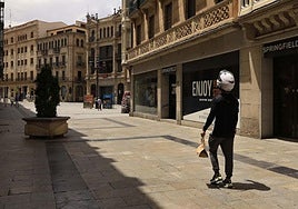 Un repartidor de comida pasea por una céntrica calle de Salamanca en un día de mucho calor.