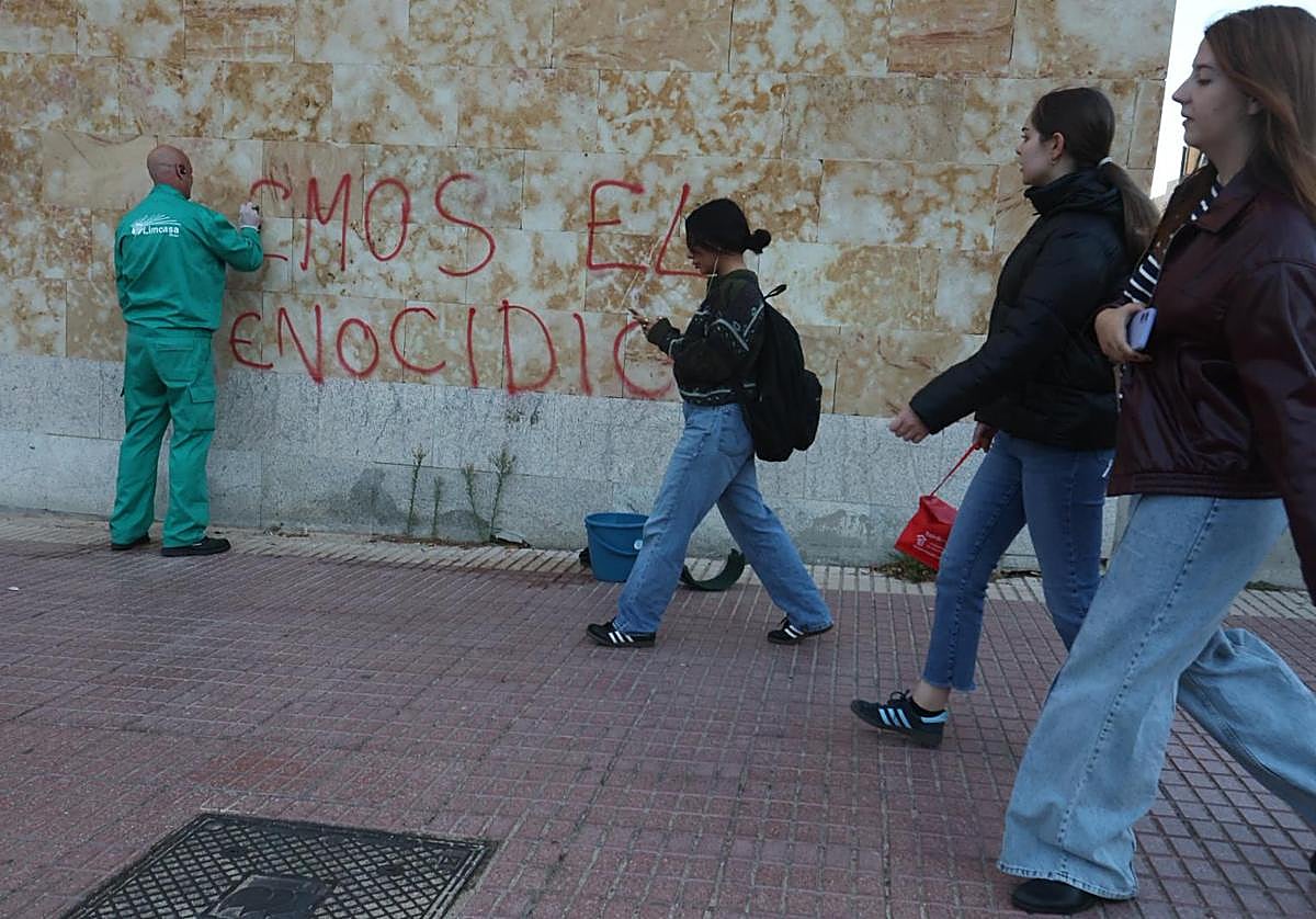Un operario trata de limpiar una pintada realizada en una facultad.
