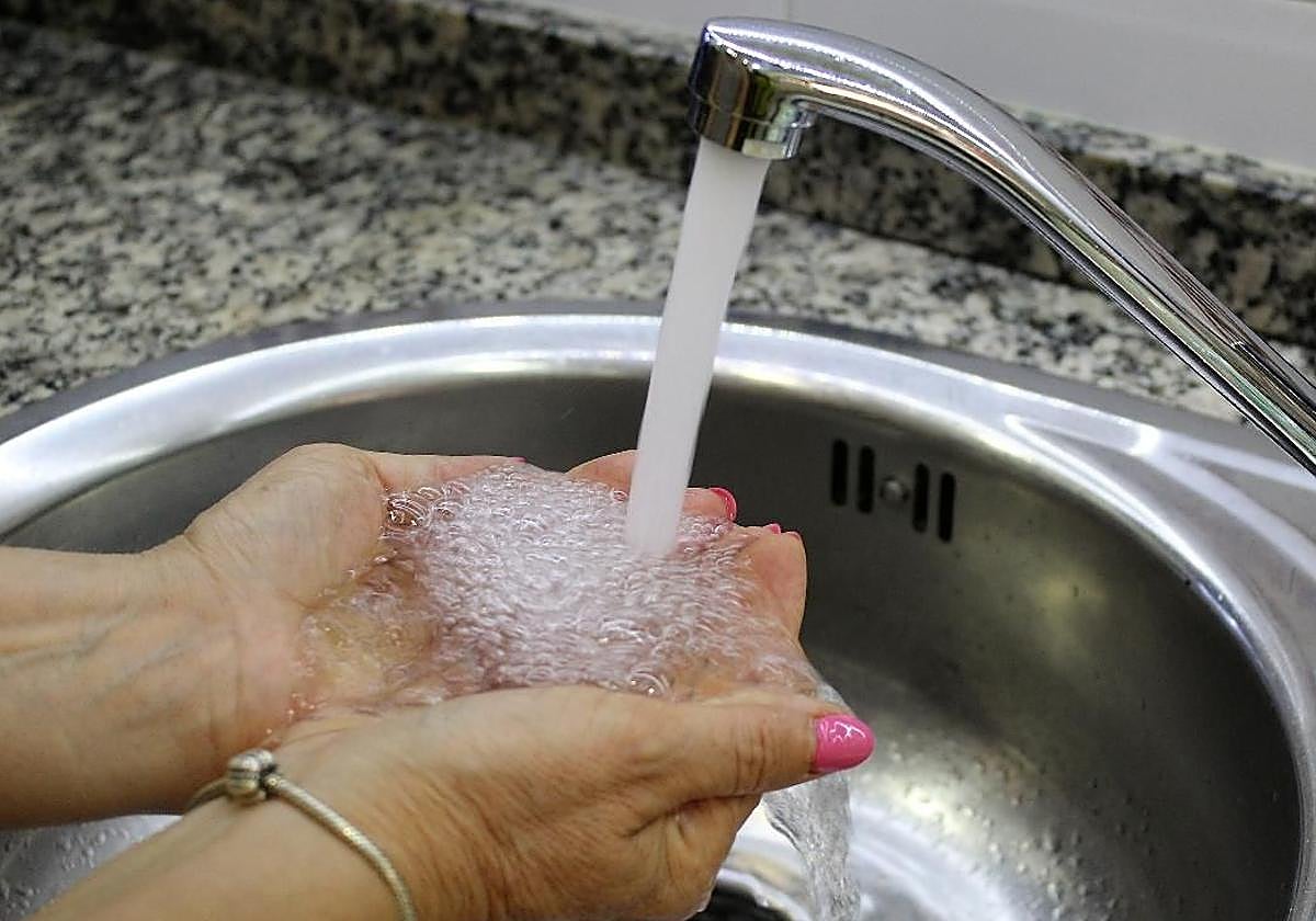 Una mujer se llena las manos con agua del grifo.