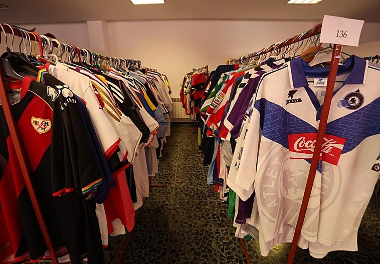 Decenas de camisetas de fútbol colgadas en perchas.