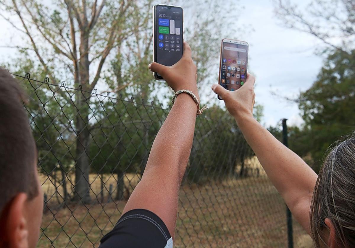 Dos personas sujetan sus móviles en el campo en una imagen de archivo.