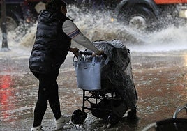 Una persona pasea con un carricoche de bebé en un día de fuerte lluvia en Salamanca.