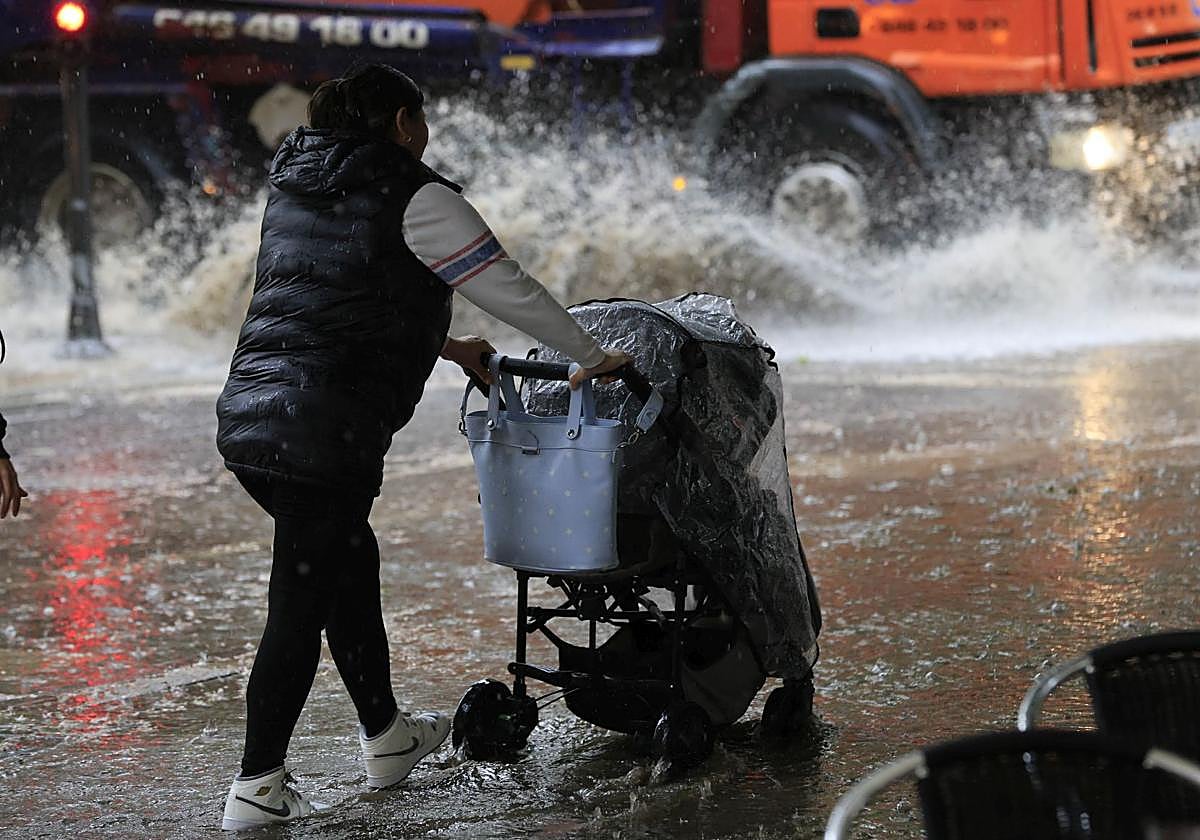 Una persona pasea con un carricoche de bebé en un día de fuerte lluvia en Salamanca.