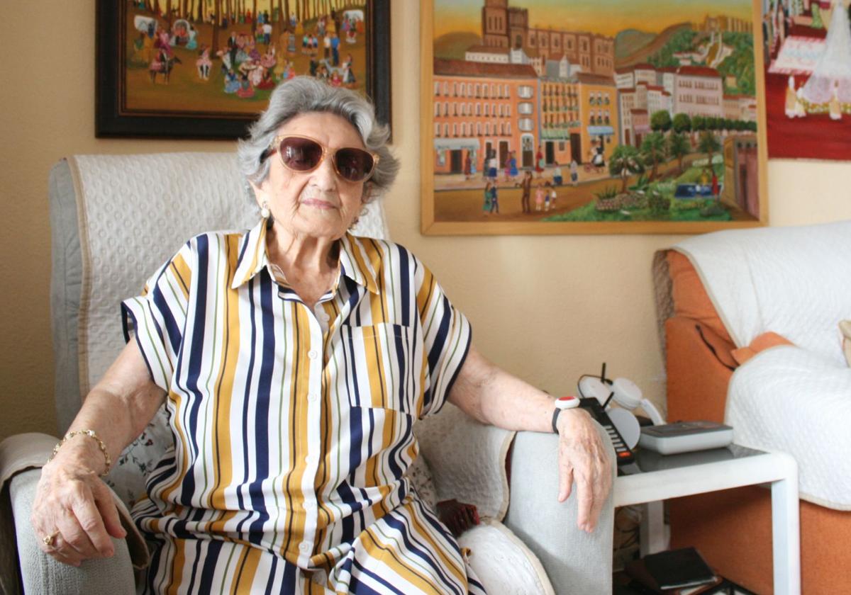 Trinidad posiert im Wohnzimmer ihres Hauses vor drei Bildern, die sie malte, nachdem sie im Alter von 70 Jahren zu malen begann.