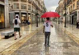 Kurze Ärmel und Regenschirme in einer untypischen Herbstszene in der Calle Larios.