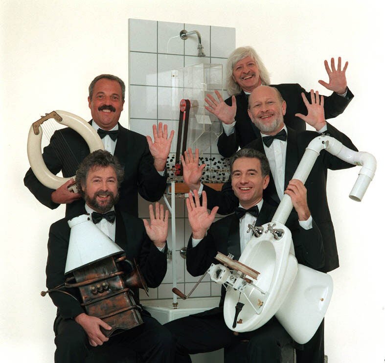 Mitglieder der Gruppe Les Luthiers mit typischen Instrumenten.