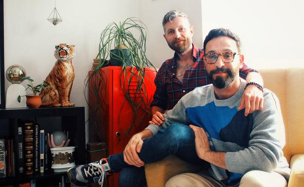 Eryk Pall and Roy Laguna, next to their static cat in their living room..