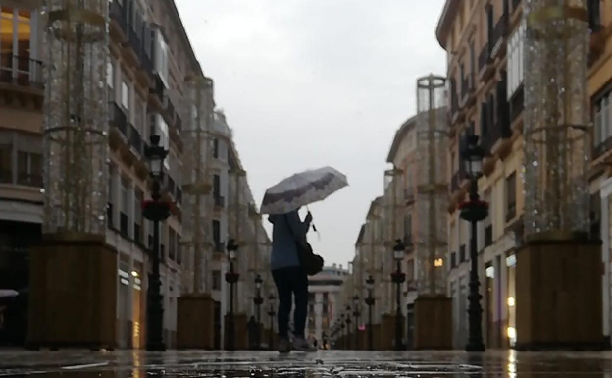 A person walking on a rainy Calle Larios. 