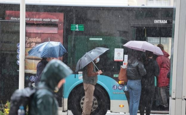 People wait for buses under umbrellas 