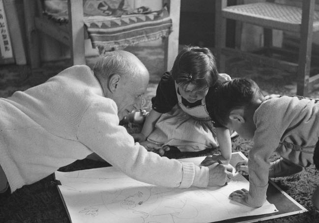 Pablo Picasso, showing his children Paloma and Claude how to paint.