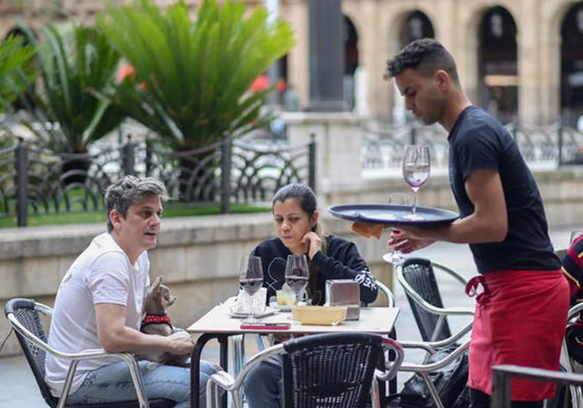 Customers and a waiter on a bar terrace.