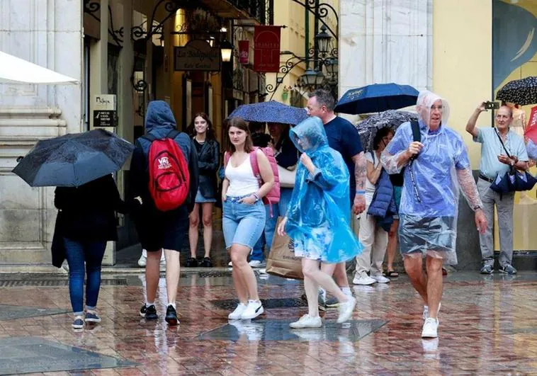 Tourists with raincoats and umbrellas, yesterday in Malaga city centre.