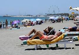 Tourists enjoy the sun and the beach on the coast of Torremolinos.