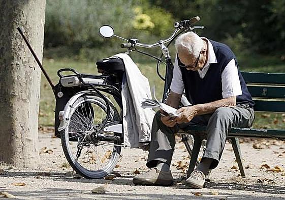A pensioner reading a newspaper in a park.