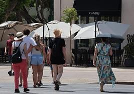 Tourists protect themselves from the sun in Malaga with umbrellas and hats on Sunday.