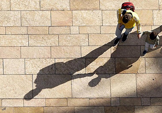 A parent walking with a child in Malaga on a sunny day.