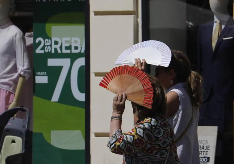 Two women use fans as protection from the sun. Archive photo.