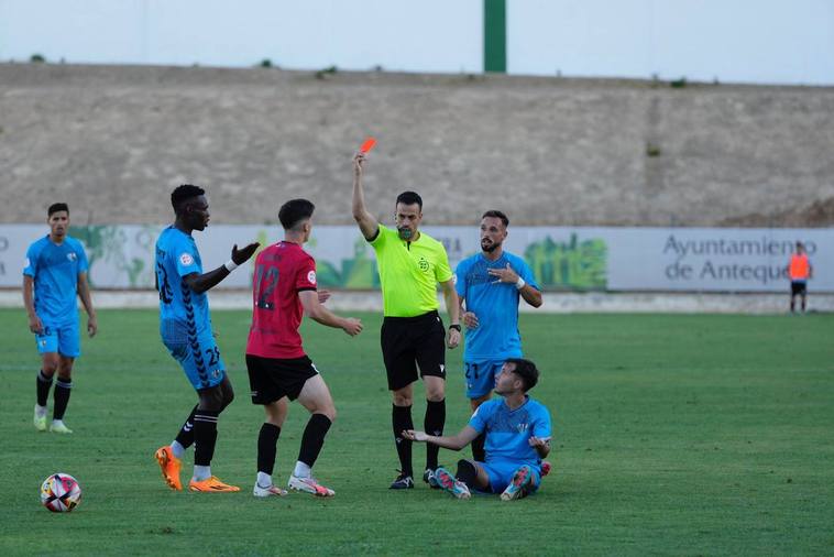 A referee holds up a red card at a match.