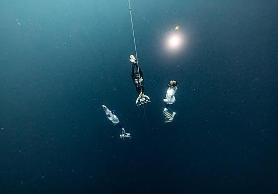 The dive. Davide Carrera, centre, rising to the surface after his 130m descent.