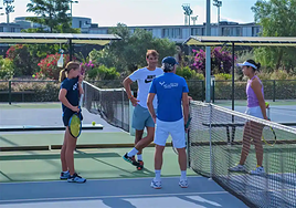 Rafa Nadal speaking with two young tennis players and a coach at his academy in Manacor.