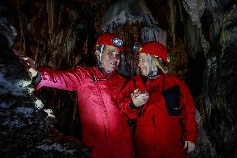 Emilio and Remedios pose in the cave holding hands.