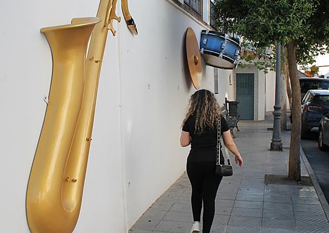 A neighbour walks among a saxophone, drums and cymbals in the Plaza del Calvario.