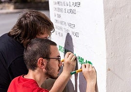 Two of the artists touching up the poems that have already been painted onto many walls.
