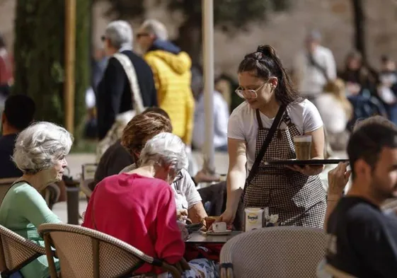 A waitress serves customers on a cafe terrace in Valencia.