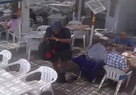 Screenshot of the video showing the alleged thief dragging one of the bags from the table with his foot