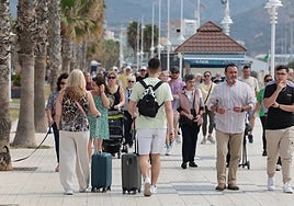 Tourists hauling their suitcases along the promenade.