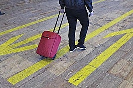 Passenger at El Prat airport, Barcelona with a carry-on suitcase.
