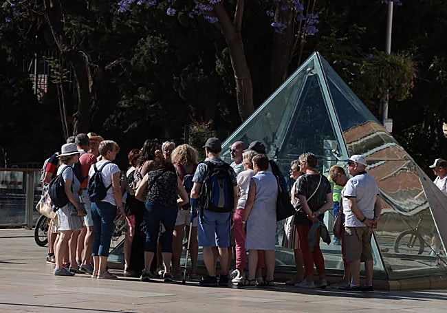 A group of tourists around the glass pyramid that provides a view of the garum basins of the Roman Theatre.