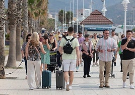 Tourists walk to their accommodation along Malaga's promenade